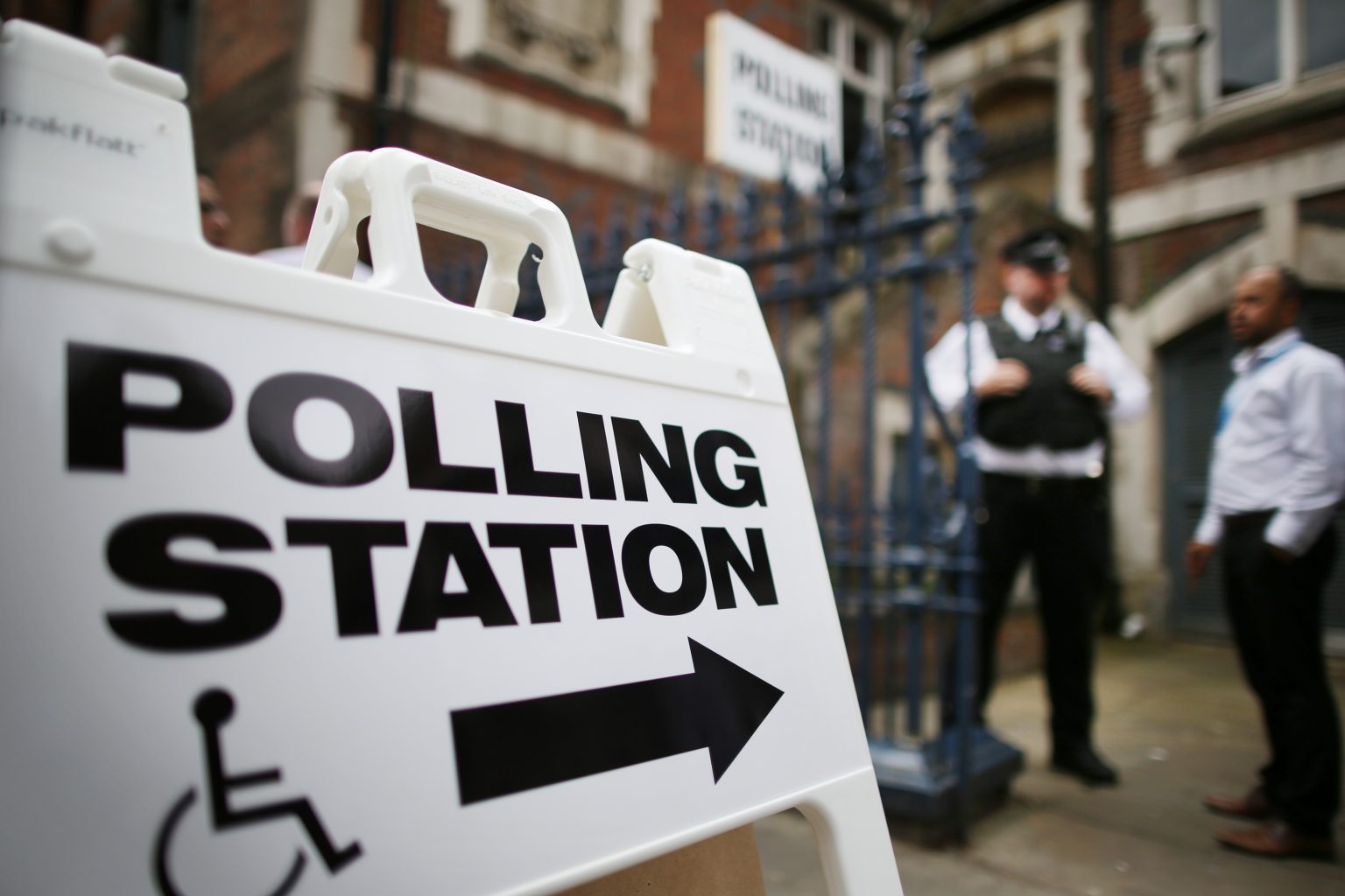 LONDON, UNITED KINGDOM - MAY 22: A policeman and an official stand outside a polling station at Christ Church Church of England Primary School in Brick Lane on May 22, 2014 in London, England. Millions of voters are going to the polls today in local and European elections.  (Photo by Peter Macdiarmid/Getty Images)