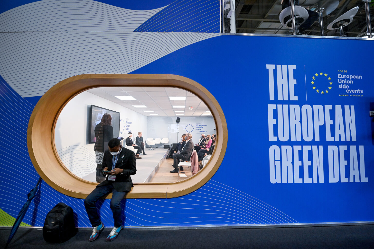 GLASGOW, SCOTLAND - NOVEMBER 12: A Delegate checks his phone outside the European Union side event stand at COP26 as negotiations continue on November 12, 2021 in Glasgow, Scotland. Day thirteen of the 2021 COP26 climate summit in Glasgow will focus on advancing action in the places we live, from communities to cities and regions.  This is the 26th "Conference of the Parties" and represents a gathering of all the countries signed on to the U.N. Framework Convention on Climate Change and the Paris Climate Agreement. The aim of this year's conference is to commit countries to net-zero carbon emissions by 2050. (Photo by Jeff J Mitchell/Getty Images)